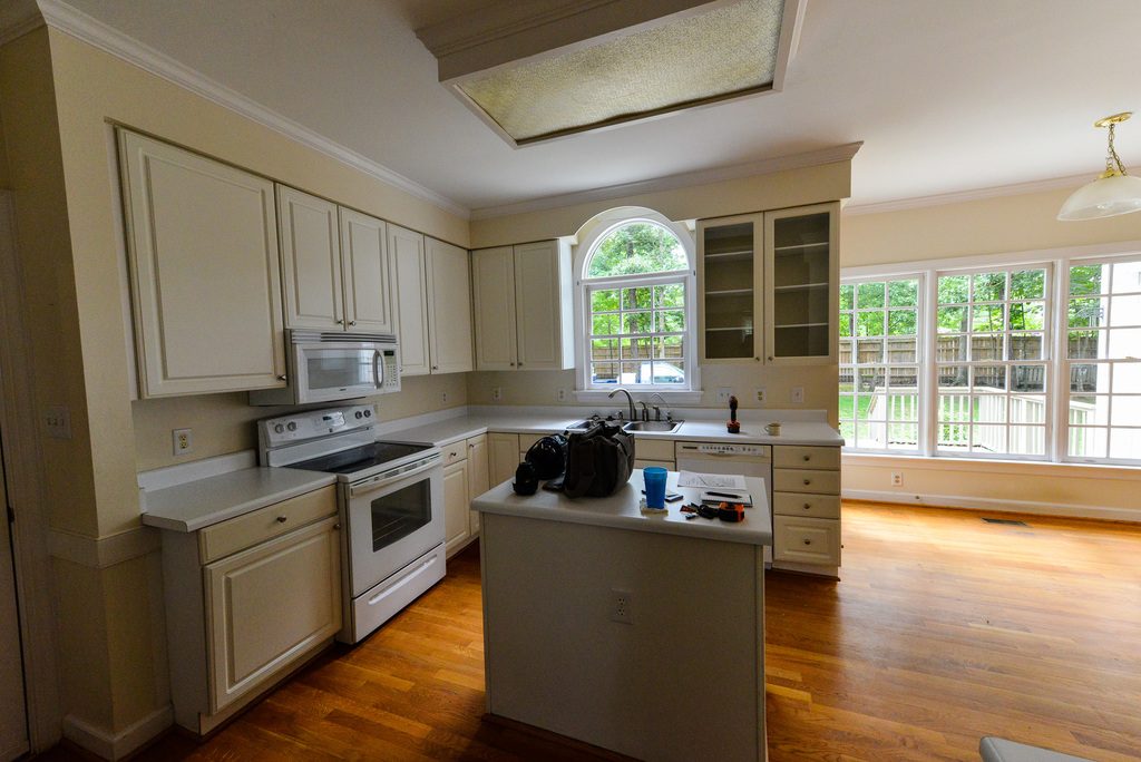 A bright kitchen with cream cabinets, an island and tall windows looking onto the garden
